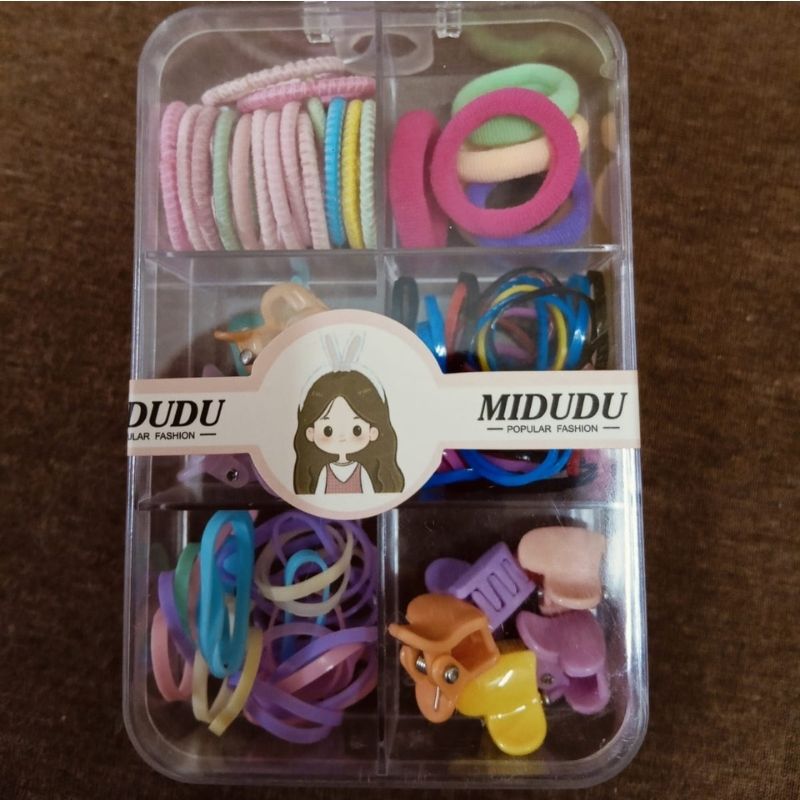 Packaged hair accessories with colorful rubber bands and clips on a brown surface
